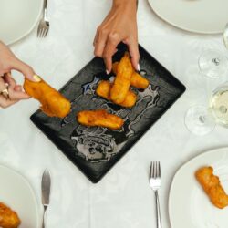 Comensales en mesa cogiendo comida, Restaurante Cruz Blanca Las Murallas